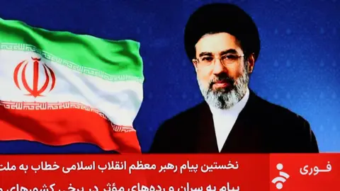 EPA A screengrab of an Iranian state TV broadcast that shows a photograph of Mojtaba Khamenei next to the flag of Iran. A red 'news ticker' in Farsi takes up the lower third of the image.