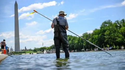 Reuters A worker in waders seen using a long pole to clean the pool