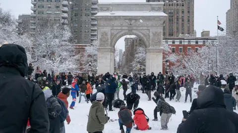 Getty Images Dozens of people play and throw snowballs in New York's Washington Square Park