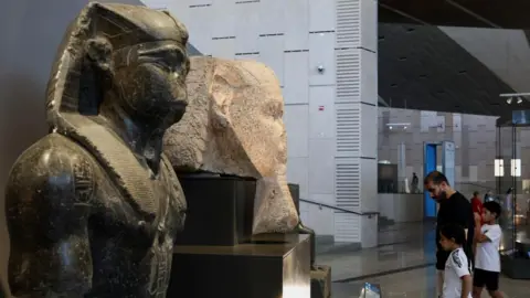Reuters Egyptians look at exhibits at the Grand Egyptian Museum (GEM), which officially opened on November 1, 2025