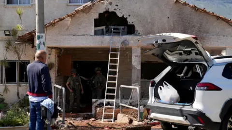 Reuters Israeli soldiers work at a house near Israel's border with Lebanon that was damaged by rocket fired by Hezbollah (3 March 2026)