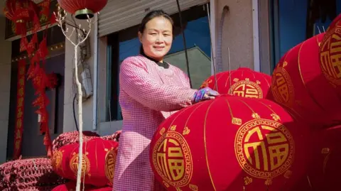 BBC Chinese woman in pink surrounded by red Lunar New Year lanterns