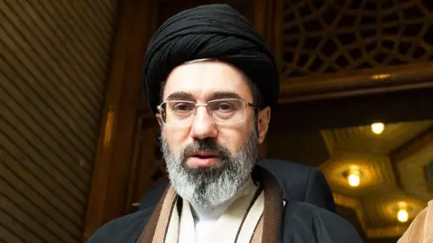AFP via Getty Images Mojtaba Khamenei looks down the lens. 