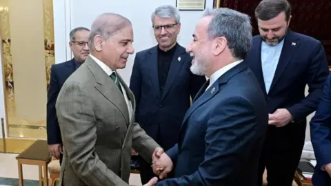 Reuters Pakistan's Prime Minister Shehbaz Shari shakes hands with Iranian Foreign Minister Abbas Araqchi 