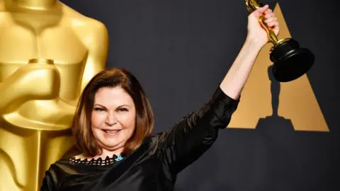 Getty Images Costume designer Colleen Atwood smiles as she raises up her golden Oscar statuette for Fantastic Beasts and Where to Find Them in 2017. 