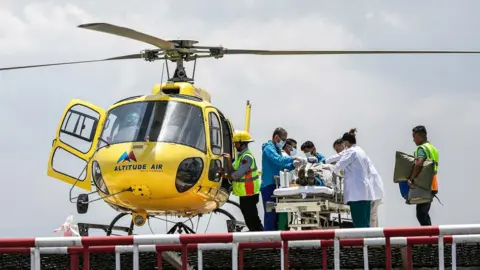 Getty Images Medical personnel attend to Dawa Sherpa, and Everest climbing guide, as they prepare to airlift him to hospital aboard a yellow helicopter