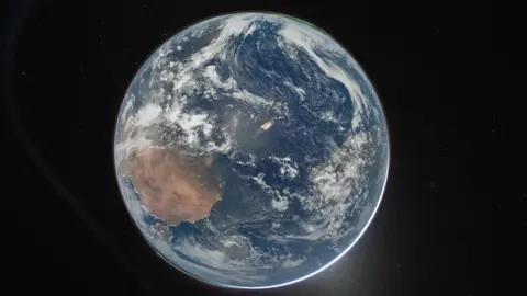 Nasa/Reid Wiseman A picture of the Earth from space, which centres the planet against the dark background of space. It's a round blue planet. Clouds can be seen and a thin green aurora at the top.