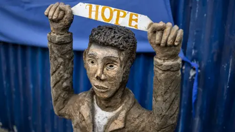 AFP via Getty Images A statue of a boy holding up a sign with the word 'Hope' at a camp for displaced people in Mekelle, Ethiopia.
