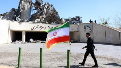 EPA An Iranian official walks next to the damaged Azadi sports complex in Tehran, Iran (3 April 2026)