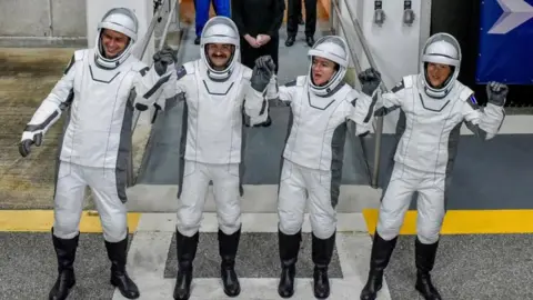 Reuters Four astronauts in white space suits hold hands and lift them in celebration at the Kenedy Space Centre entrance