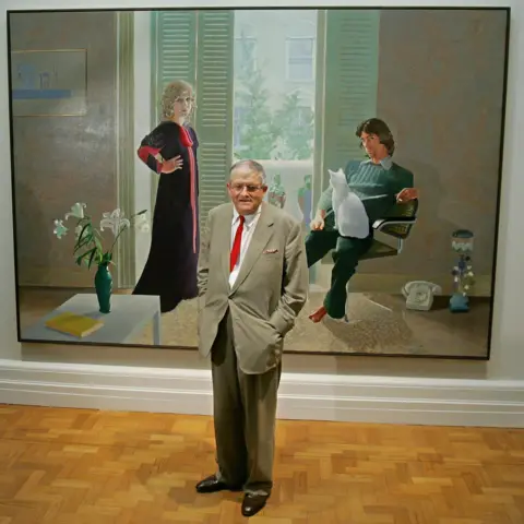 Getty Images David Hockney poses in front of his painting entitled 'Mr and Mrs Clark and Percy' (1970) at the National Portrait Gallery in London, 11 October 2006