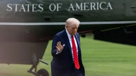Getty Images Donald Trump holds his hand up to the camera after stepping out of Marine One
