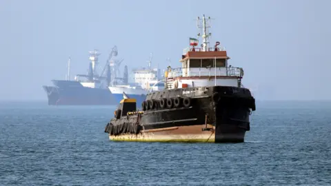 AFP via Getty Images An Iran-flagged tugboat sails near a ship anchored in the Strait of Hormuz off Bandar Abbas in southern Iran