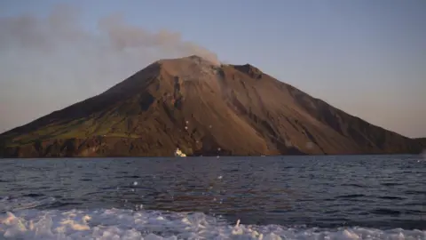 Anadolu via Getty Images A puff of smoke emanates from the top of Stromboli volcano, pictured from sea 
