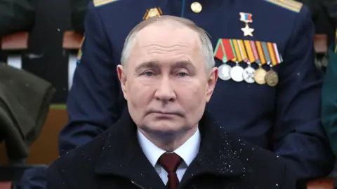 EPA Vladimir Putin stares straight into the camera at a military parade in Moscow, with a dusting of snow on his black overcoat