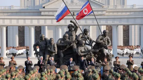 KCNA via Reuters Wide shot showing North Korean leader Kim Jong Un speaking to soldiers wearing military uniforms as he stands on a monument in Pyongyang for Russian soldiers who died in the Ukraine war