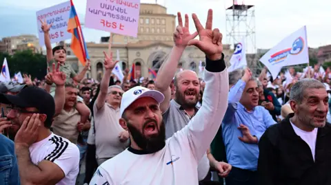 Getty Images A crowd of people, appearing to be mainly men, wave flags and placards, with many raising their arms. They are identified as supporters of Strong Armenia, the party of billionaire Russian-Armenian businessman Samvel Karapetyan.