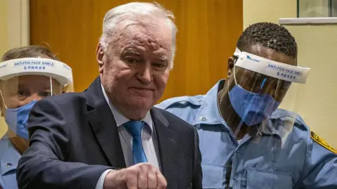 AFP via Getty Images Former Bosnian Serb military chief Ratko Mladić arrives in the courtroom prior to the hearing of the final verdict on appeal against his genocide conviction over the 1995 Srebrenica massacre