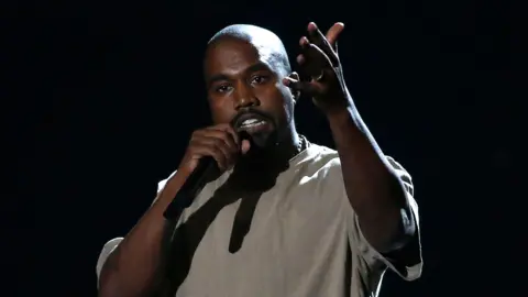 Reuters Kanye West on stage holding microphone 
