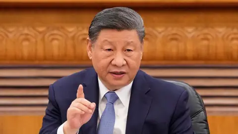 Getty Images Chinese President Xi Jinping wears a dark blue suit and blue tie and is seen gesturing while talking