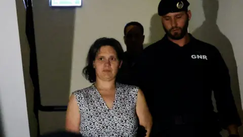 Getty Images Frenchwoman Marine R. leaving the Setubal courthouse on Saturday, she is being escorted by a police officer.