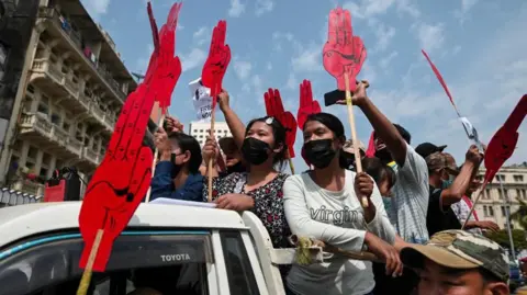 Reuters Young anti-coup protesters hold signs depicting the now iconic three-finger salute