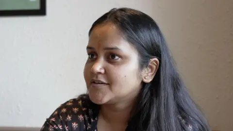 Tariq Khan/BBC Hindi Aishanya Dwivedi, wearing a brown printed blouse with her hair open, looks at someone to the side of the camera.