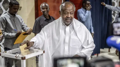 AFP via Getty Images Ismail Omar Guelleh, dressed in white and facing the cameras, casts his vote at in Djibouti city on 10 April 2026