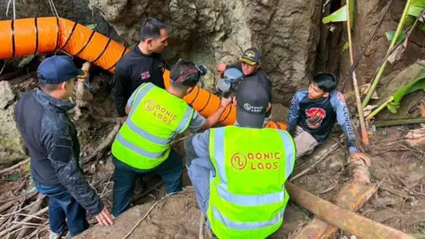 Metta Tham Rescue Kalasin Rescuers trying to fix an orange pump onto one of the cave's entrances