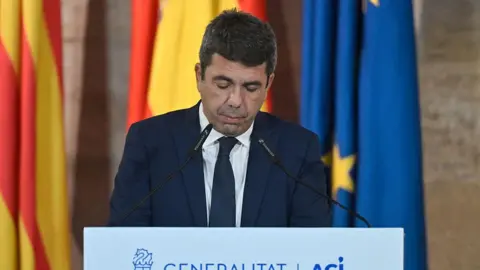 Getty Images Carlos Mazon standing in front of a lectern with a microphone, looking down