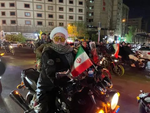 Armed men on motorcycles waving Iranian flags in the centre of Tehran