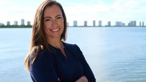 Emily Gregory campaign Emily Gregory, the Democratic nominee for Florida state house district 87, stands in front of a waterway with buildings in the background.