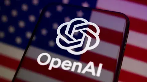 Getty Images A phone with the white OpenAI logo on it, in the background is the American flag