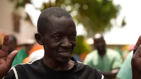 Amensisa Negera / BBC Daniel Kitambala smiles with one hand raised