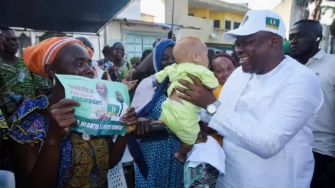 Reuters Presidential candidate Paul Hounkpe of FCBE (Force Cauris pour un Benin Emergent) holds a baby during a campaign rally ahead of the presidential election scheduled for April 12, in Cotonou, Benin April 1, 2026