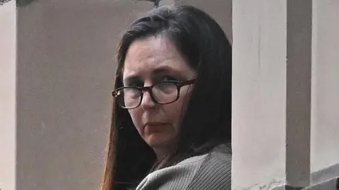 EPA Erin Patterson, wearing glasses and a grey sweater, look at the camera