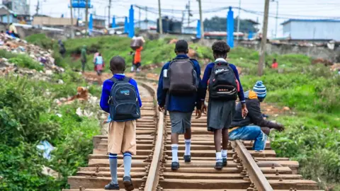 Donwilson Odhiambo/Getty Images Children in school uniform walk along a train line in Nairobi, Kenya - Monday 13 May 2024
