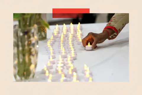Reuters A woman lays a candle to join rows of others