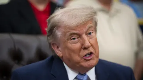 EPA/Shutterstock US President Donald Trump sits on a leather chair and speaks
