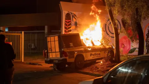 Rhett Hammerton/EPA A police vehicle is set alight during clashes between community members and law enforcement outside Alice Springs Hospital.