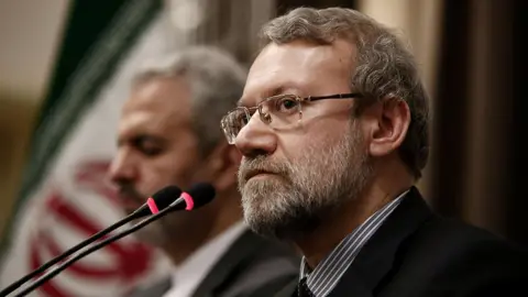 Anadolu via Getty Images Ali Larijani in a black suit. 