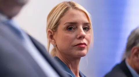 Getty Images A blonde woman wearing pink lipstick looks straight ahead, her hair is in a ponytail and she is wearing a blue blazer