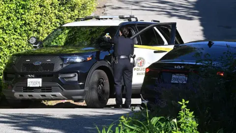 Getty Images/DUTCH/Bauer-Griffin/Contributor A police vehicle is parked on a road with an officer standing next to it