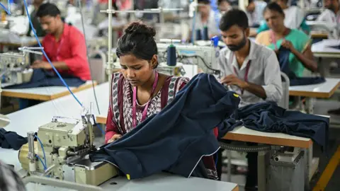 AFP via Getty Images A woman employee wearing a red traditional Indian suit work at a garment factory in Tiruppur, in India's southern state of Tamil Nadu
