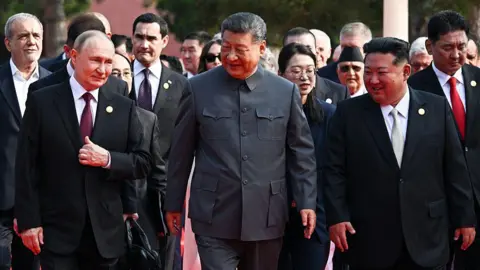 Getty Images (L-R) Russia's President Vladimir Putin walks with China's President Xi Jinping and North Korea's leader Kim Jong Un
