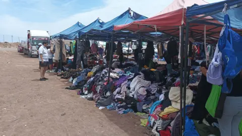 Second-hand clothes on sale from tents at an outdoor market in the Chilean town of Alto Hospicio