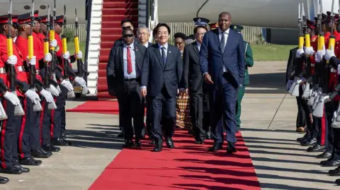 Taiwan Presidential Office Handout Taiwan President Lai Ching-te walks along a red carpet beside an aircraft, flanked by an honour guard with rifles and accompanied by Eswatini Prime Minister Russell Dlamini