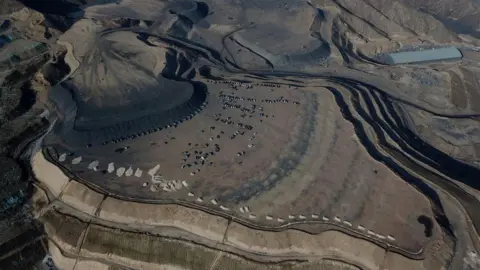 Getty Images Aerial view shows coal being loaded onto trucks near a coal mine in Datong, China's northern Shanxi province on November 2, 2021. 