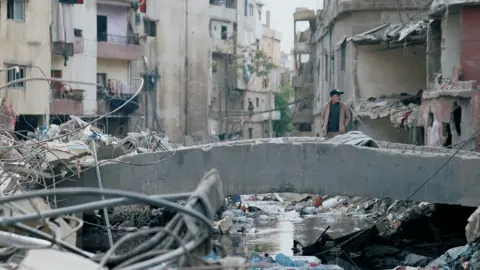 A man stands on a bridge surveying destruction in Beirut after the 8 April attack