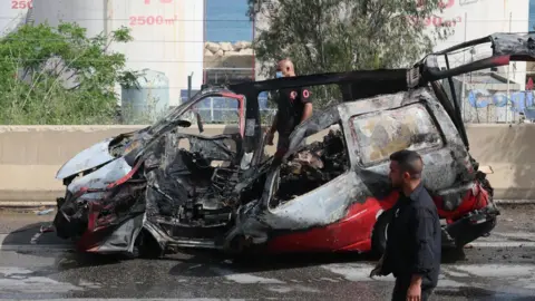 EPA Lebanese rescuers and army soldiers inspect the wreckage of a vehicle that was hit in an Israeli strike in Jiyeh, south of Beirut, Lebanon (13 May 2026)